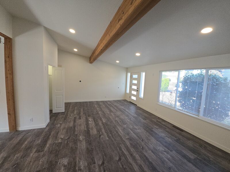 Vaulted living room with exposed wood beam and large windows