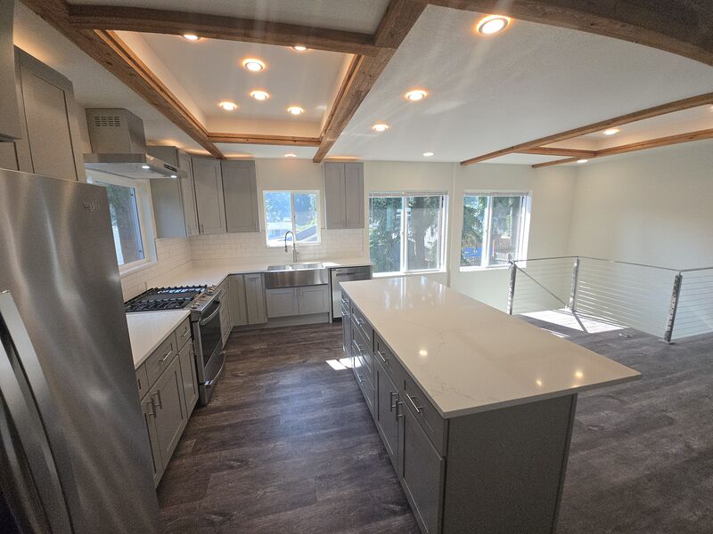 Remodeled main kitchen with large island, quartz counters, and stainless appliances