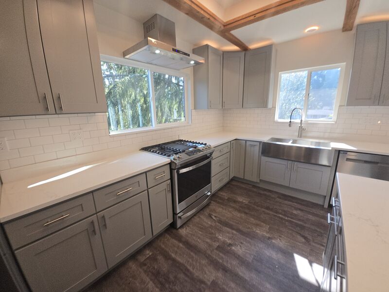 Kitchen gas range with subway-tile backsplash and windows over the sink