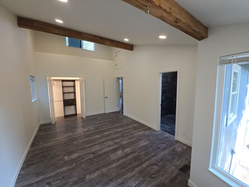 Primary bedroom with vaulted beamed ceiling and bright windows