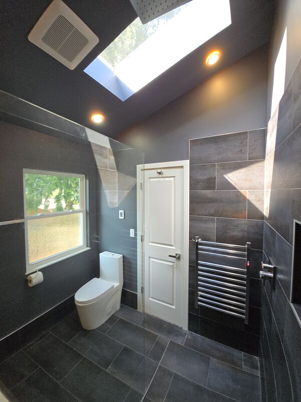 Bathroom with dark tile, skylight, heated towel rail, and window