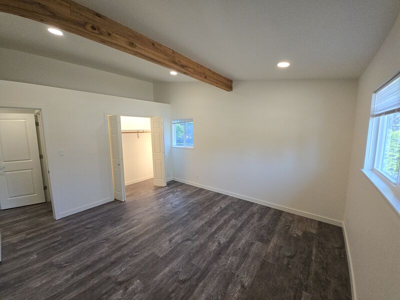 Second bedroom with wood-beam ceiling accent and closet