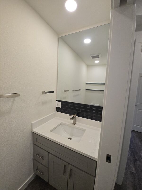Powder room with modern vanity, mirror, and fixtures