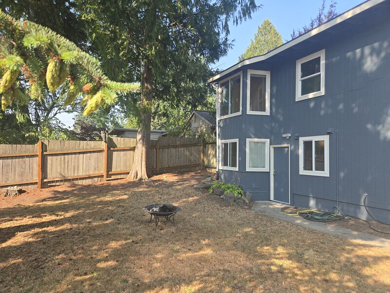 Fenced back yard with fire pit, utility shed, and the home's daylight lower level