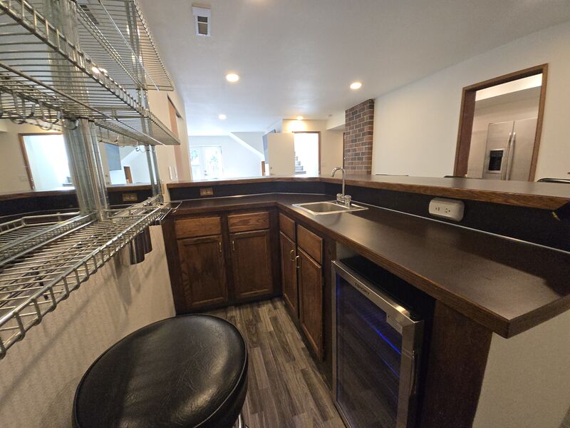 Lower-level wet bar and second kitchen with beverage fridge, bar sink, and seating